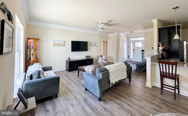 living room with ceiling fan, crown molding, light wood-type flooring, and baseboards