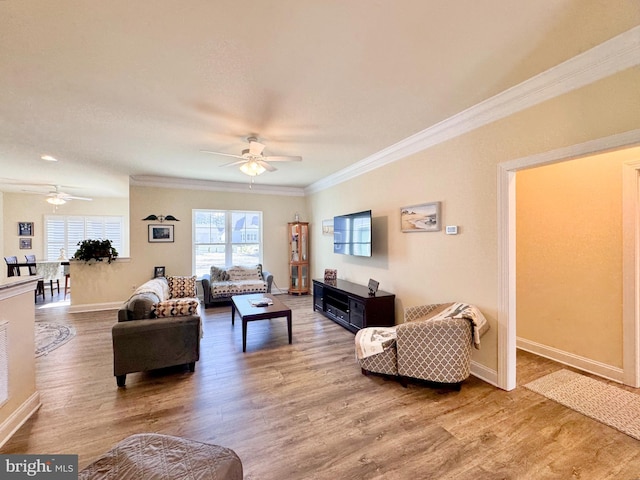 living area featuring baseboards, wood finished floors, a ceiling fan, and ornamental molding