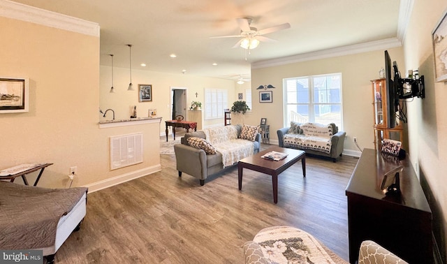 living room featuring wood finished floors, baseboards, visible vents, ceiling fan, and ornamental molding