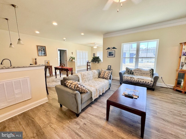 living room featuring a ceiling fan, wood finished floors, visible vents, and baseboards