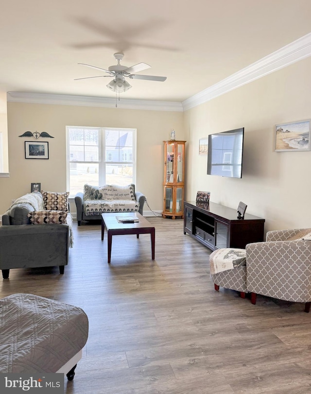 living room featuring ceiling fan, baseboards, wood finished floors, and crown molding