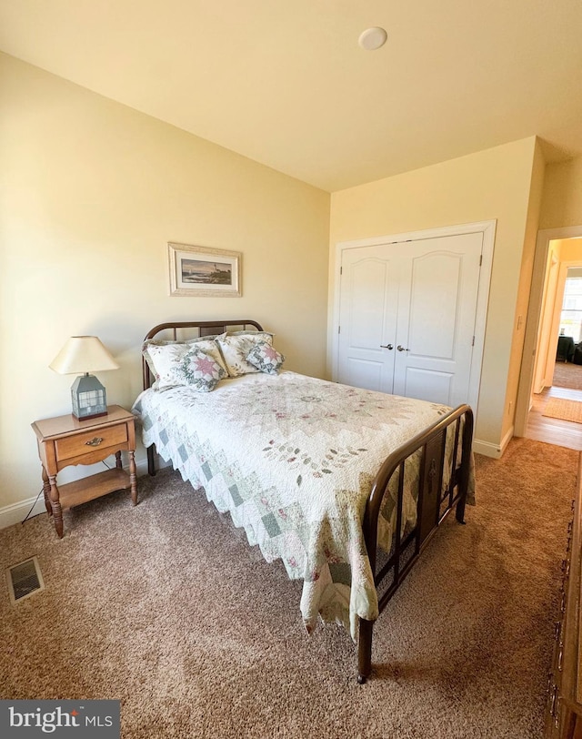 carpeted bedroom featuring visible vents, baseboards, and a closet