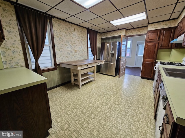 kitchen featuring light floors, stainless steel fridge with ice dispenser, under cabinet range hood, and wallpapered walls