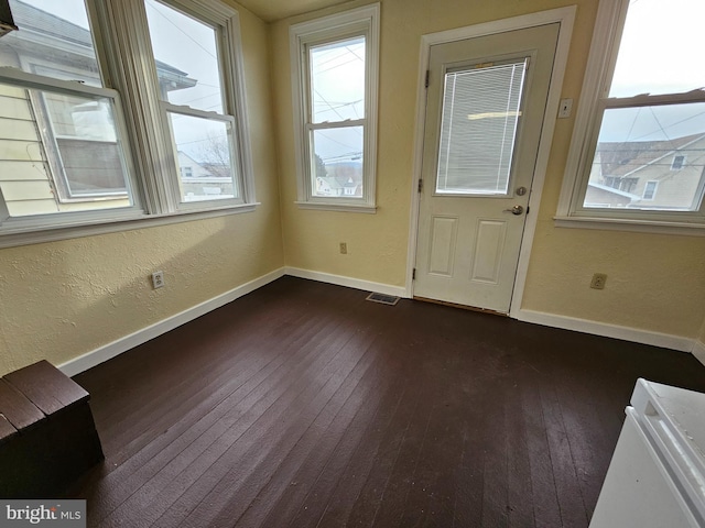 doorway to outside featuring dark wood finished floors, visible vents, and baseboards