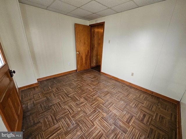 empty room with a paneled ceiling and baseboards