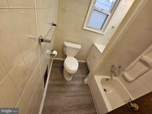 bathroom with visible vents, toilet, wood finished floors, a bathtub, and tile walls