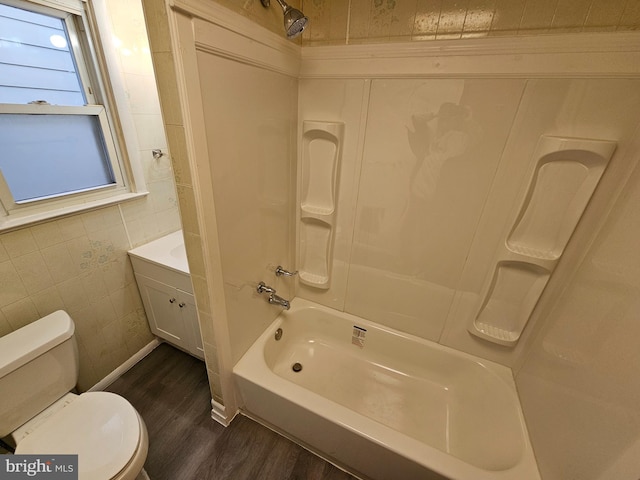 bathroom with toilet,  shower combination, tile walls, and wood finished floors