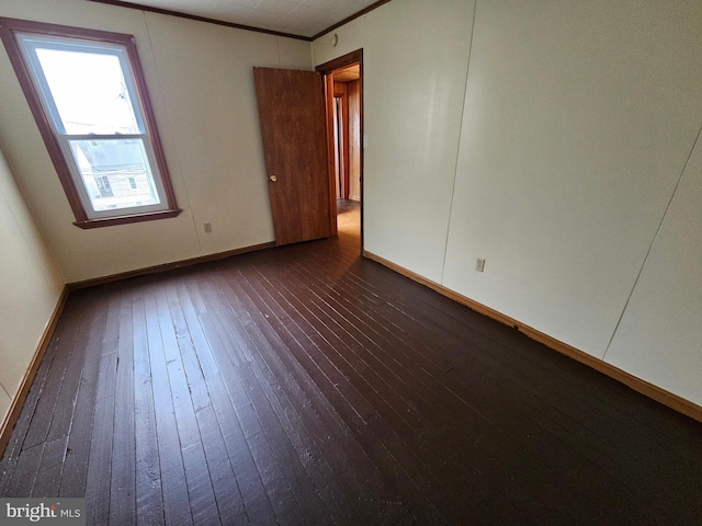 unfurnished room with dark wood-style floors, baseboards, and crown molding