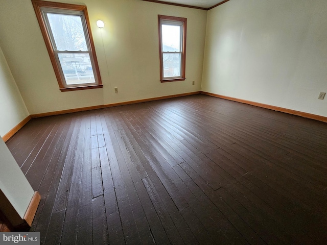 spare room featuring dark wood-type flooring and baseboards