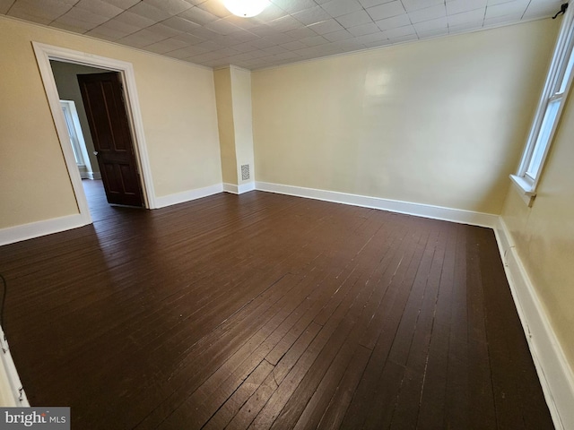 spare room featuring dark wood-type flooring and baseboards