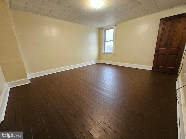 empty room featuring dark wood finished floors and baseboards