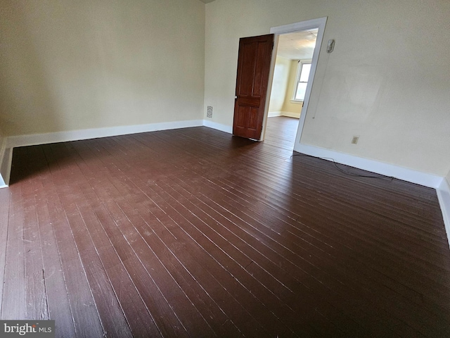 empty room with dark wood finished floors and baseboards