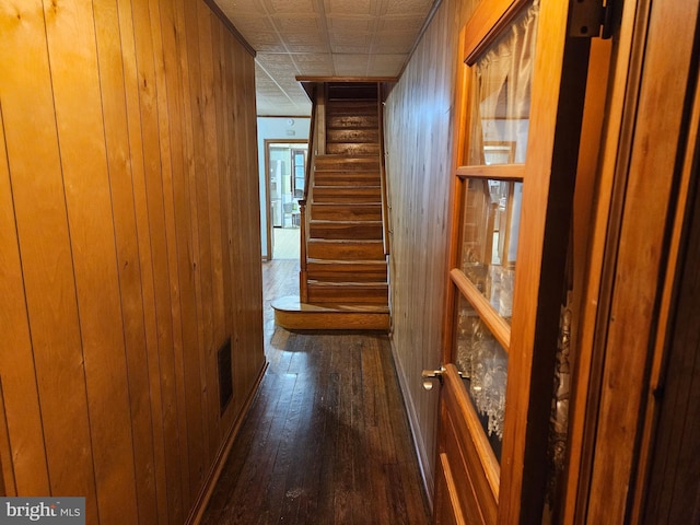 hall featuring visible vents, dark wood-style floors, an ornate ceiling, stairs, and wood walls