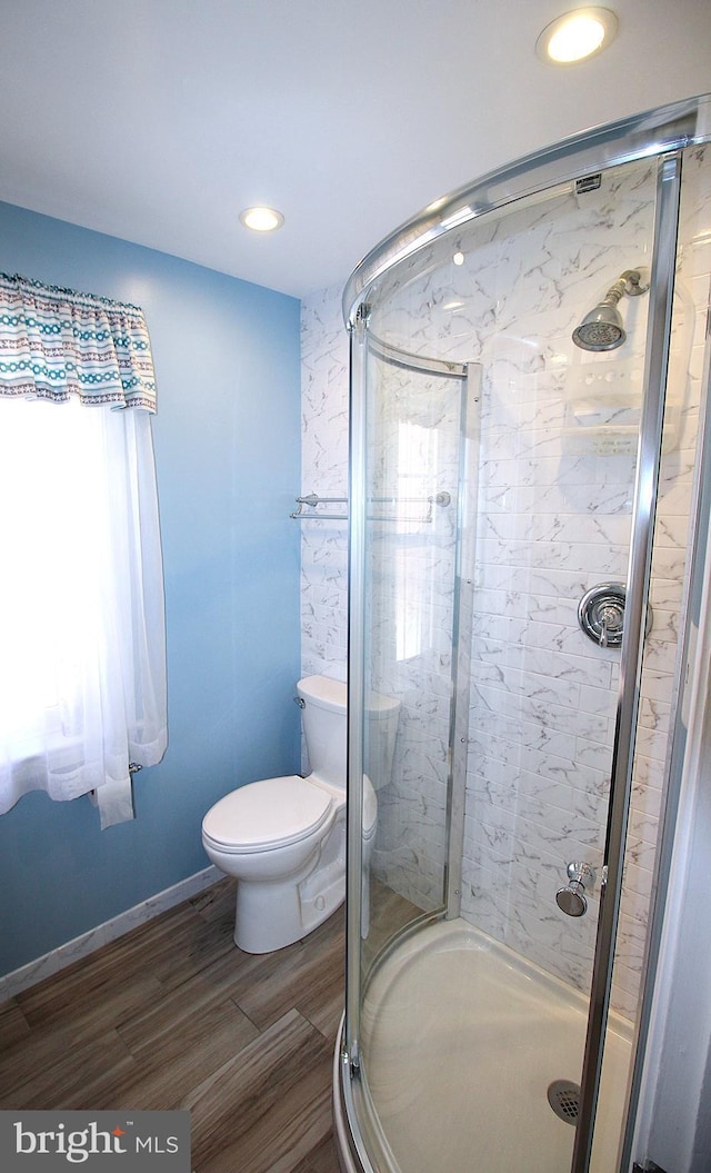 bathroom with toilet, recessed lighting, wood finished floors, baseboards, and a shower stall