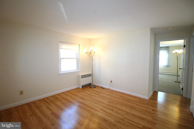 empty room with a healthy amount of sunlight, light wood-type flooring, radiator heating unit, and baseboard heating