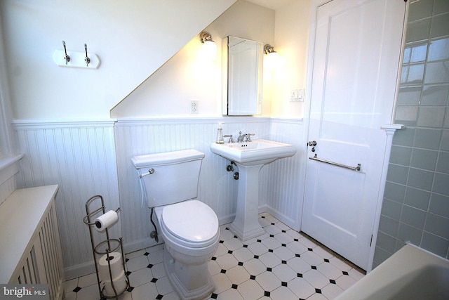 bathroom featuring radiator heating unit, toilet, wainscoting, a sink, and tile patterned floors