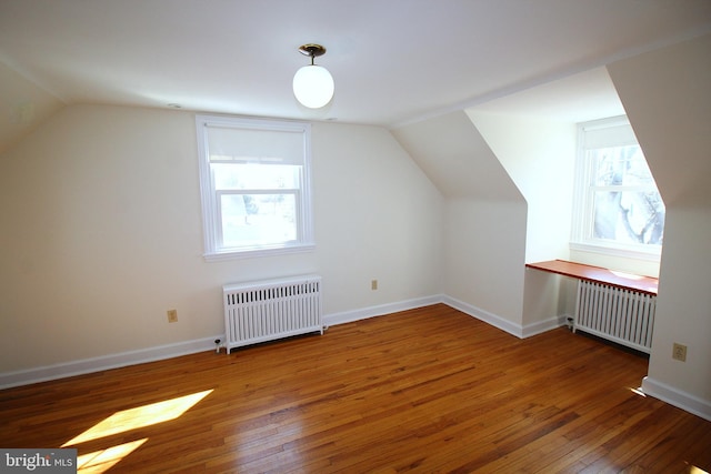 bonus room featuring radiator, a healthy amount of sunlight, wood-type flooring, and radiator heating unit