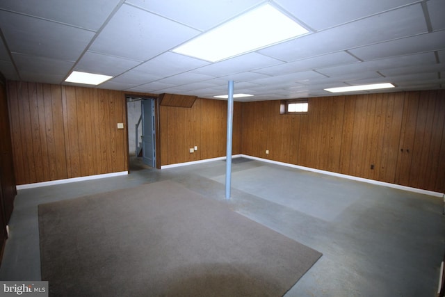 below grade area featuring wood walls and baseboards