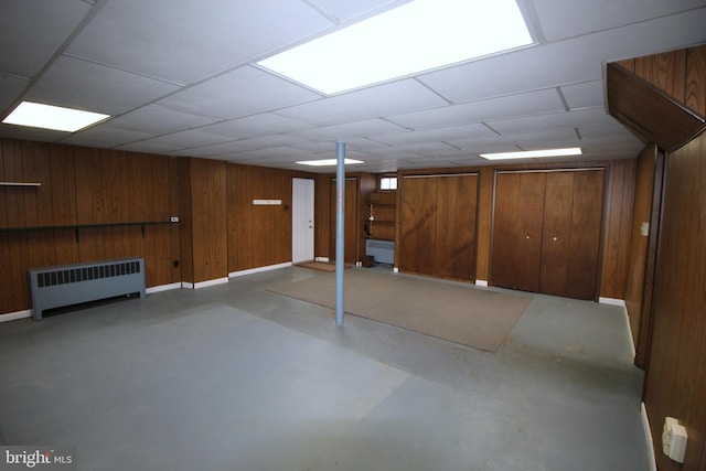 finished below grade area with radiator, wood walls, and baseboards