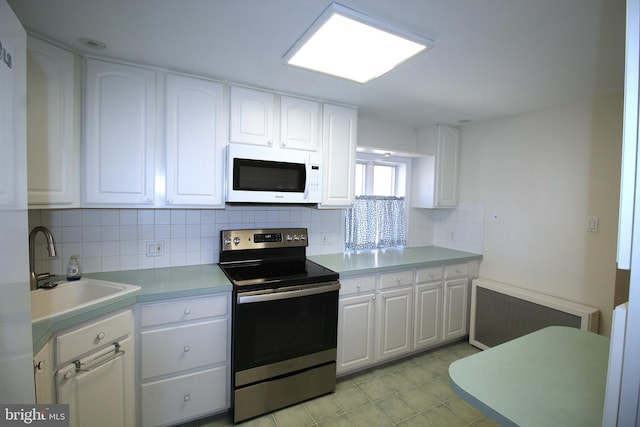 kitchen featuring white cabinets, white microwave, radiator heating unit, stainless steel electric stove, and a sink