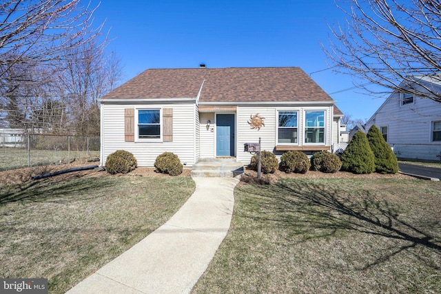 view of front of property featuring a front lawn, fence, and roof with shingles