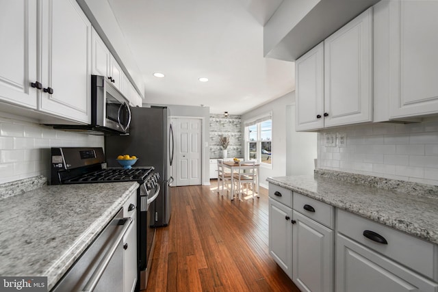 kitchen with decorative backsplash, appliances with stainless steel finishes, dark wood finished floors, and white cabinetry