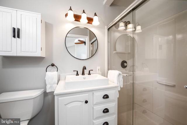 bathroom with a shower stall, vanity, and toilet