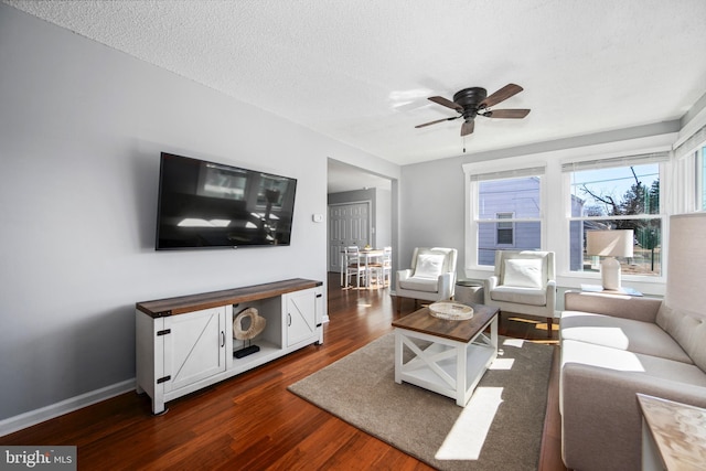 living room with dark wood finished floors, baseboards, a textured ceiling, and a ceiling fan