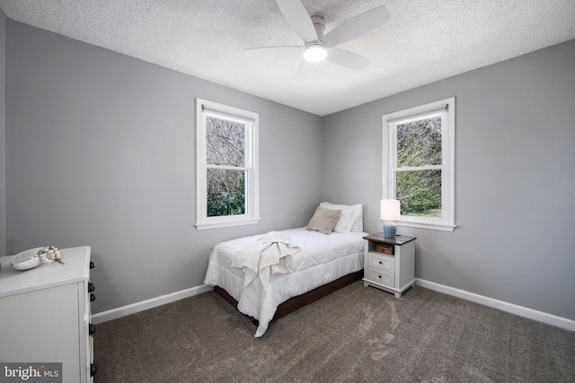 bedroom with baseboards, dark carpet, and a textured ceiling