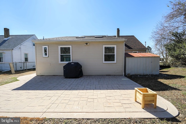 back of property featuring a patio area, fence, an outdoor structure, and a shed