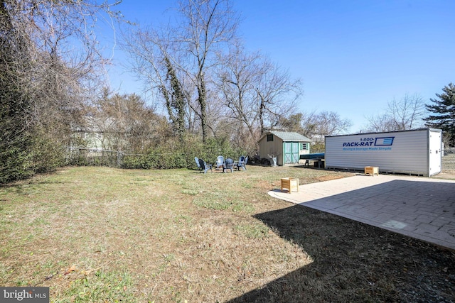 view of yard featuring a storage shed, fence, and an outdoor structure