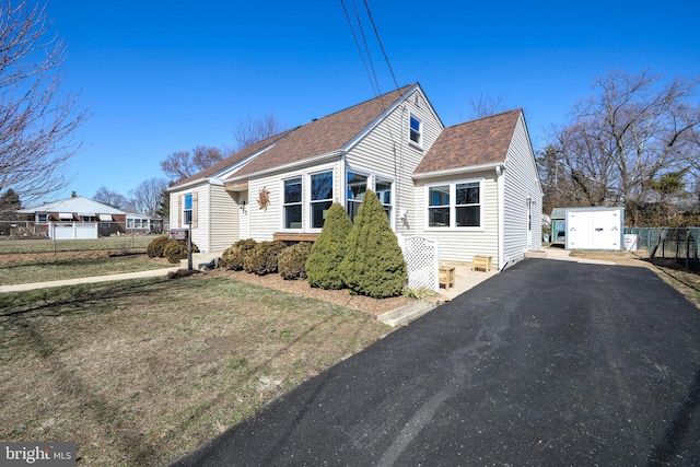 bungalow-style home featuring aphalt driveway, a front yard, roof with shingles, and fence