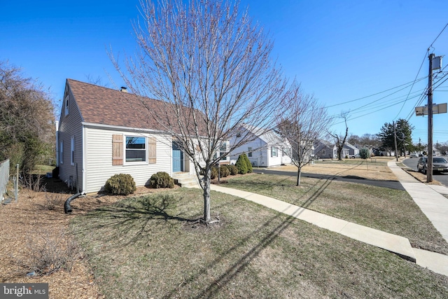 view of front of property featuring roof with shingles and a front yard