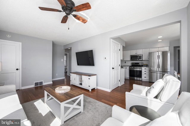 living room with dark wood-style floors, visible vents, and baseboards