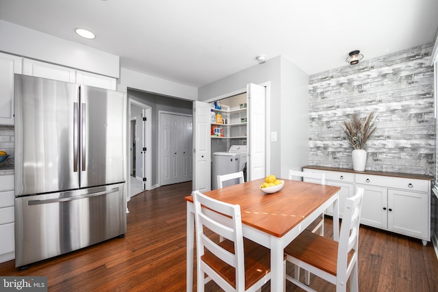 dining space featuring washer and dryer, an accent wall, and dark wood-style flooring