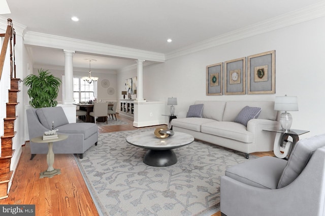 living room with recessed lighting, an inviting chandelier, ornamental molding, wood finished floors, and ornate columns