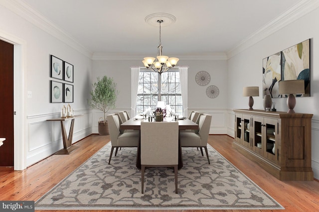 dining space featuring light wood-style flooring, a chandelier, and ornamental molding