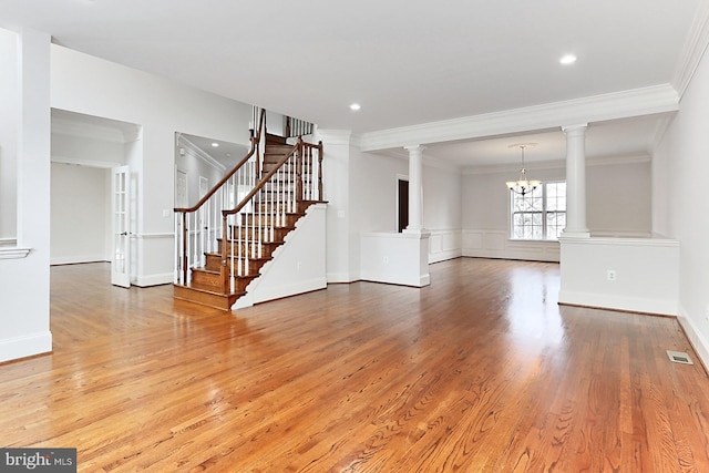 interior space with decorative columns, visible vents, ornamental molding, wood finished floors, and stairs