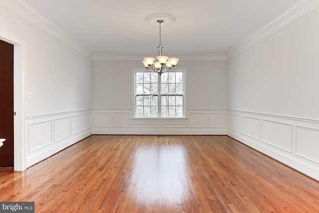 unfurnished room with a chandelier, ornamental molding, and light wood-style floors