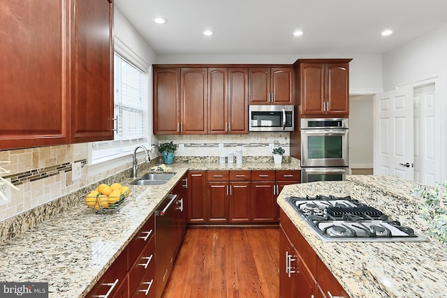 kitchen featuring dark wood-style floors, stainless steel appliances, recessed lighting, a sink, and light stone countertops