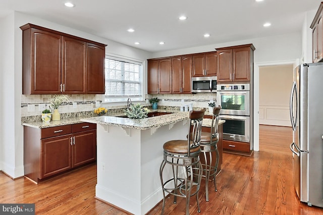 kitchen with appliances with stainless steel finishes, backsplash, a breakfast bar area, and a center island