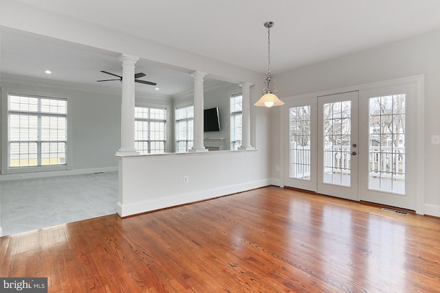 interior space featuring ornamental molding, wood finished floors, visible vents, and ornate columns