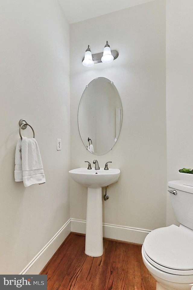 bathroom with toilet, a sink, baseboards, and wood finished floors