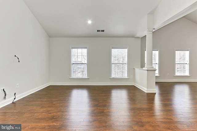 unfurnished living room featuring visible vents, dark wood-type flooring, vaulted ceiling, and decorative columns