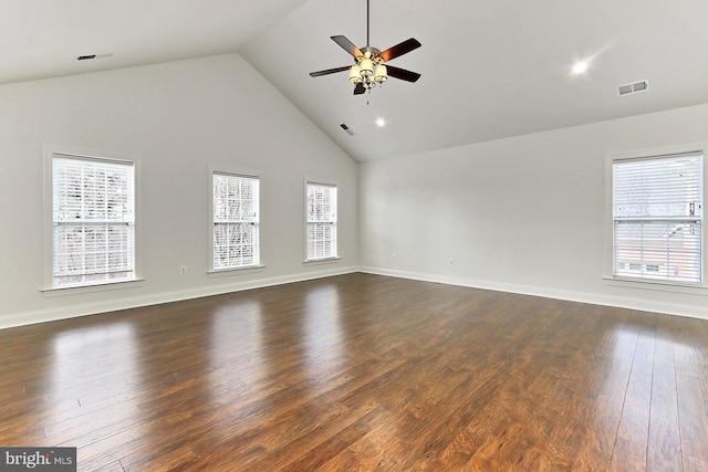 spare room featuring dark wood-style floors, a healthy amount of sunlight, high vaulted ceiling, and visible vents