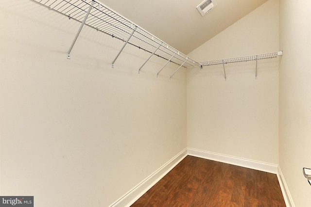 spacious closet with lofted ceiling, dark wood-style flooring, and visible vents