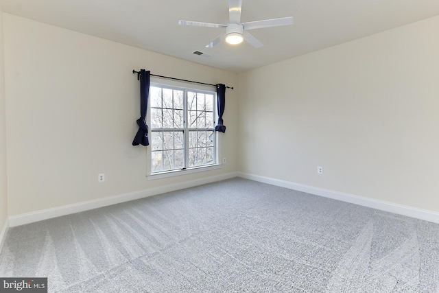 carpeted spare room featuring visible vents, a ceiling fan, and baseboards