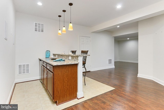 kitchen with brown cabinetry, a breakfast bar, and visible vents