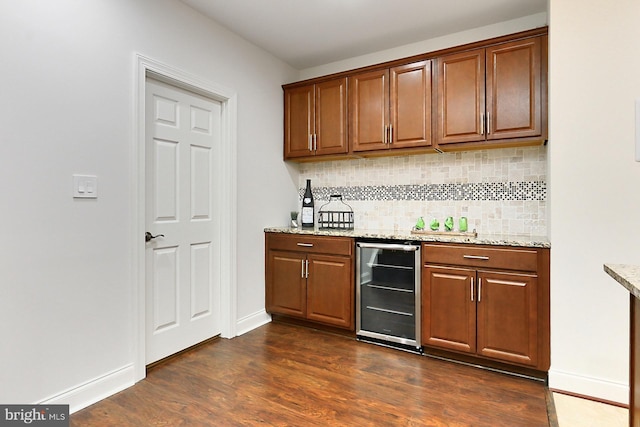 kitchen featuring dark wood-type flooring, wine cooler, decorative backsplash, and light stone counters