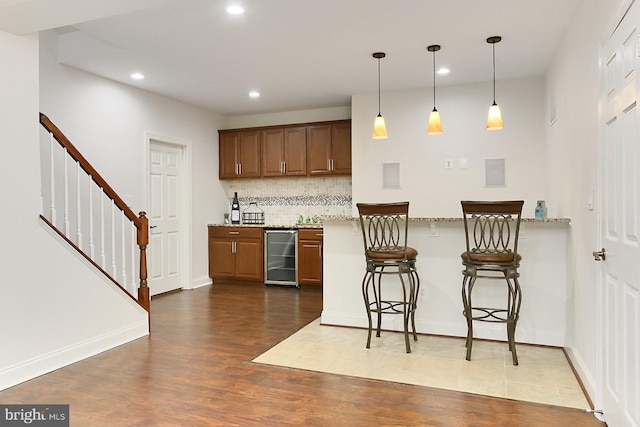 kitchen featuring wine cooler, tasteful backsplash, recessed lighting, dark wood-type flooring, and a kitchen breakfast bar